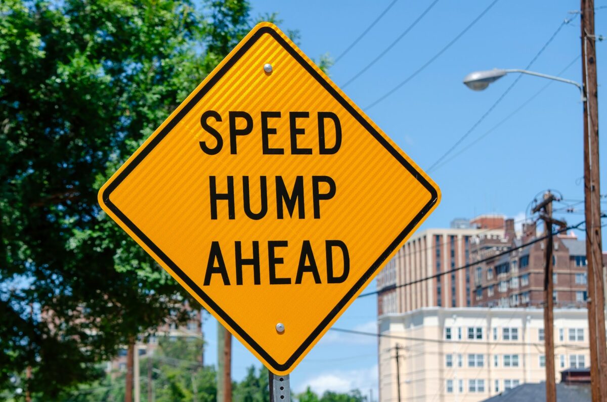 a yellow speed hump sign sitting on the side of a road